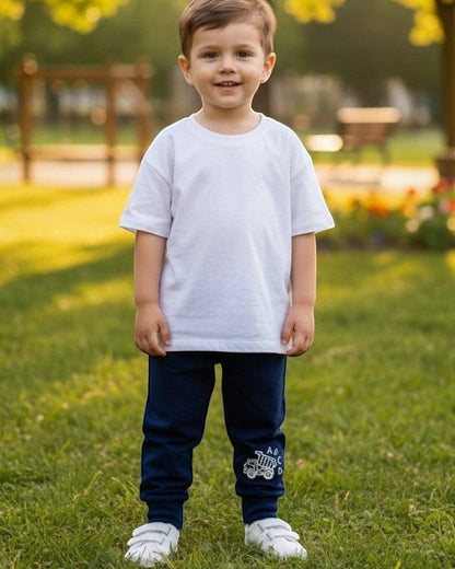 Toddler wearing Calla Lily Cosmetics + CL kids blue cotton-blend joggers with a dump truck graphic in a park.