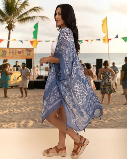 Woman wearing a blue viscose kimono cardigan with white paisley print and tassels at a beach festival by Calla Lily Cosmetics + CL kids