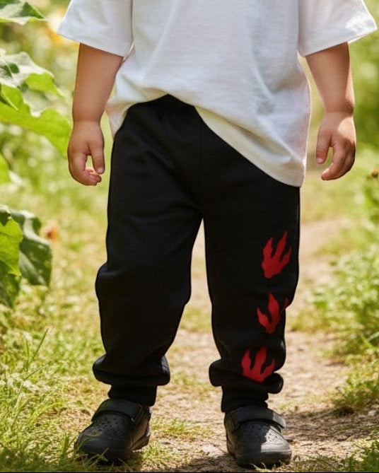 Toddler wearing Calla Lily Cosmetics + CL kids black cotton-blend joggers with red dragon paw prints in a garden.