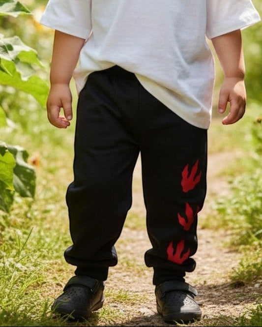 Toddler wearing Calla Lily Cosmetics + CL kids black cotton-blend joggers with red dragon paw prints in a garden.