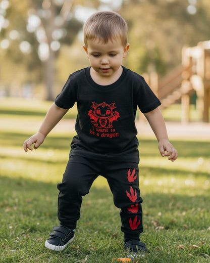 Toddler wearing a black Calla Lily Cosmetics + CL kids cotton tee with a red dragon graphic in a park setting.