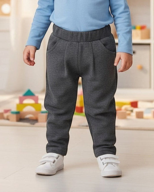 Little Who gray jersey joggers with front pockets worn by a smiling toddler in a playroom by Calla Lily Cosmetics + CL kids