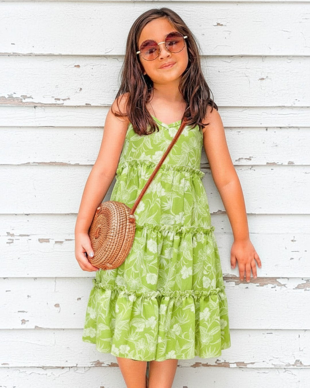 Girl wearing a green floral rayon maxi dress by Calla Lily Cosmetics + CL kids with a round rattan crossbody bag.