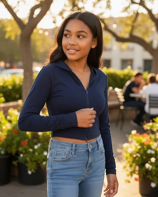 Model wearing a navy French Terry crop zip-up hoodie by Calla Lily Cosmetics + CL kids in an outdoor setting.