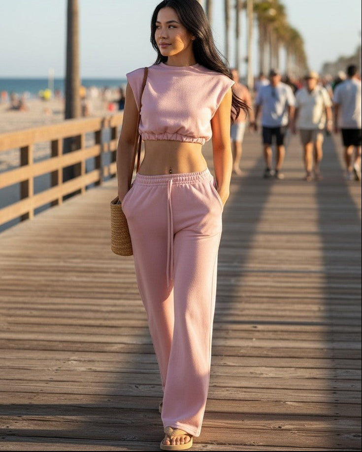 Model wearing Calla Lily Cosmetics + CL kids pink cotton French terry crop top and wide-leg pants on a beach boardwalk.