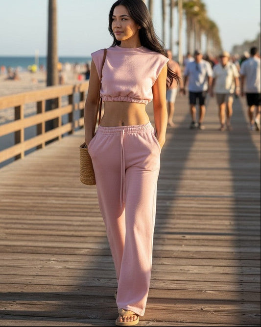 Model wearing Calla Lily Cosmetics + CL kids pink cotton French terry crop top and wide-leg pants on a beach boardwalk.
