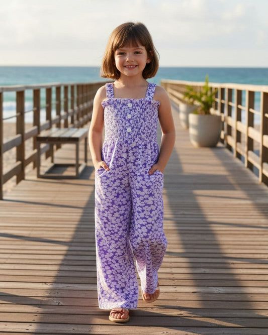 Girl wearing a light purple floral rayon romper with a smocked top and side pockets by Calla Lily Cosmetics + CL kids