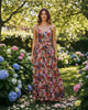 Model wearing a Calla Lily Cosmetics + CL kids red floral maxi dress with an open lace back in a garden setting.