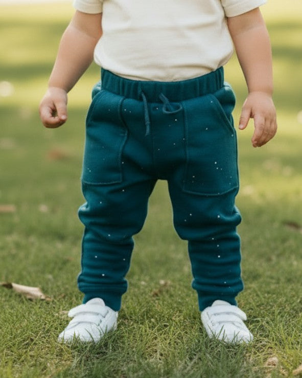 Toddler wearing Calla Lily Cosmetics + CL kids teal cotton joggers with white specs in a park setting.