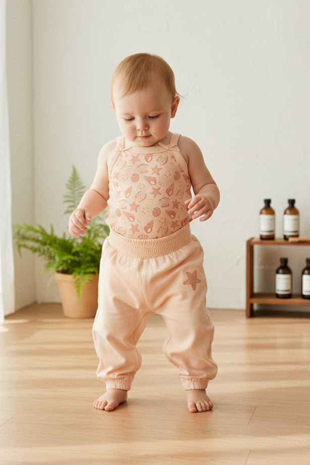 Calla Lily Cosmetics + CL kids 3-piece baby set: peach seashell print bodysuit, striped bodysuit with pufferfish, and peach pants with starfish accent.