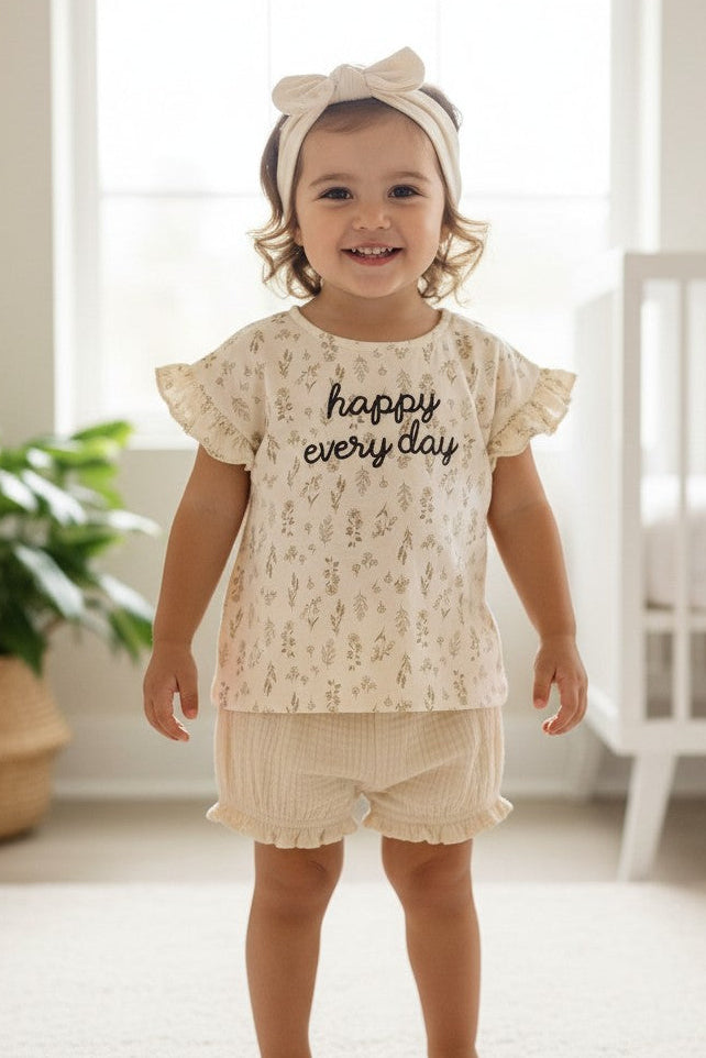 Calla Lily Cosmetics + CL kids cream cotton baby girl set with floral print top and ruffle shorts. "happy every day" text.