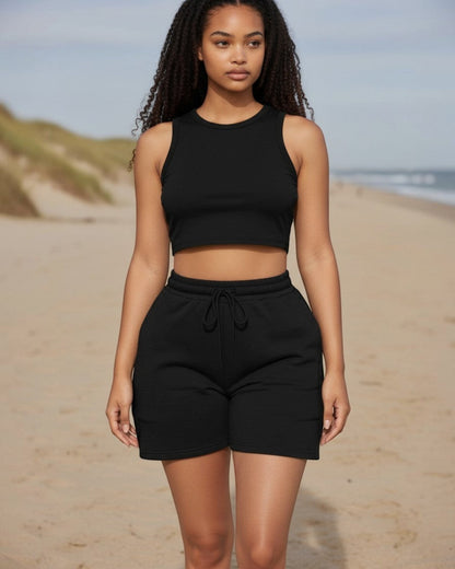 Model wearing a black Calla Lily Cosmetics + CL kids two-piece set with a fitted crop tank and drawstring shorts.