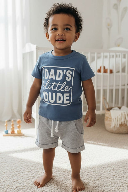 Calla Lily Cosmetics + CL kids blue graphic tee with "DAD'S little DUDE" text and grey shorts with drawstring. Cotton-polyester blend.