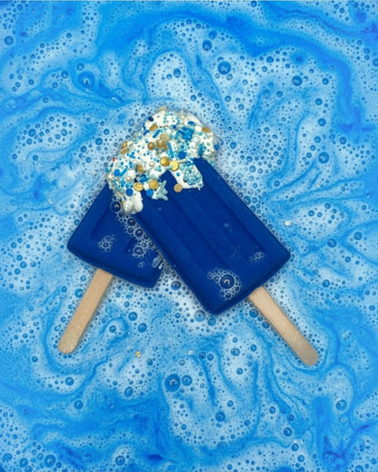 Calla Lily Cosmetics + CL kids blue popsicle bath bomb fizzing in water with white foam and decorative sprinkles