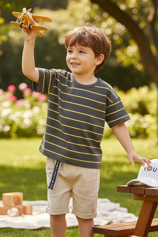 Calla Lily Cosmetics + CL kids boys grey t-shirt with yellow stripes, paired with beige shorts and white sneakers.