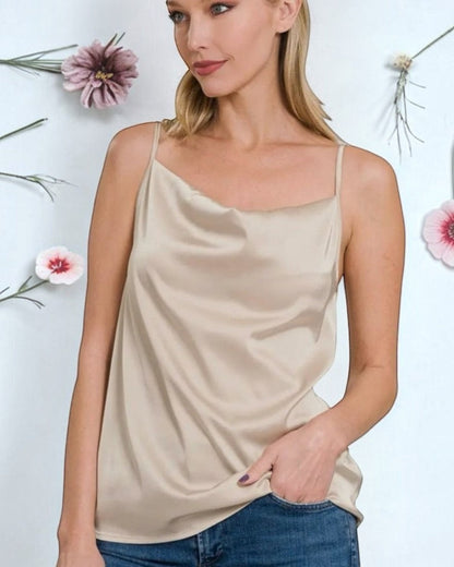 Model wearing a Calla Lily Cosmetics + CL kids cream satin cowl neck cami top with thin straps against a floral backdrop