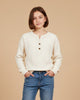 Girl wearing a Calla Lily Cosmetics + CL kids cream thermal waffle knit Henley with a three-button placket and jeans.