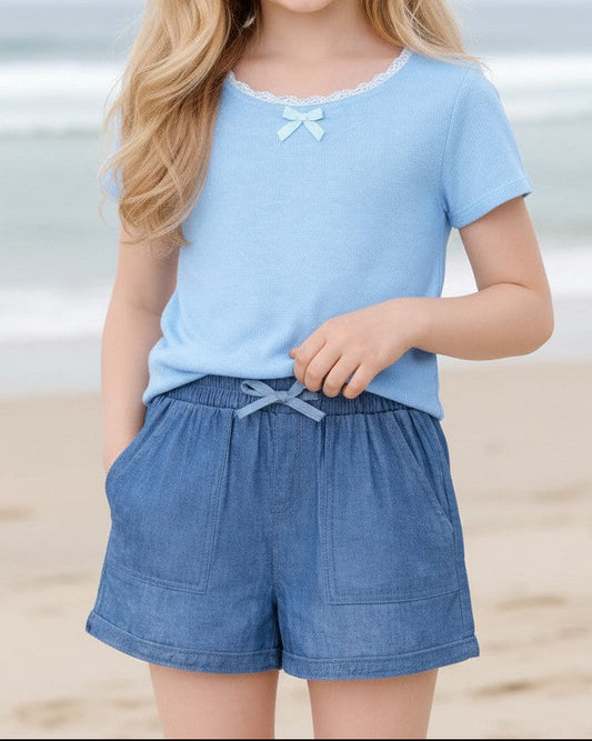 Calla Lily Cosmetics + CL kids denim blue chambray shorts with drawstring waist and pockets, worn by a smiling young girl.