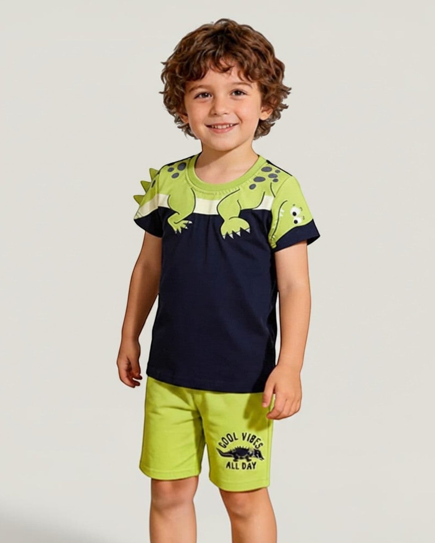 Calla Lily Cosmetics + CL kids boys navy blue cotton t-shirt with green dinosaur graphic and lime green shorts with "Cool Vibes All Day" print.