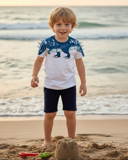 Calla Lily Cosmetics + CL kids white cotton t-shirt with blue dinosaur graphic and navy shorts. Boy model.