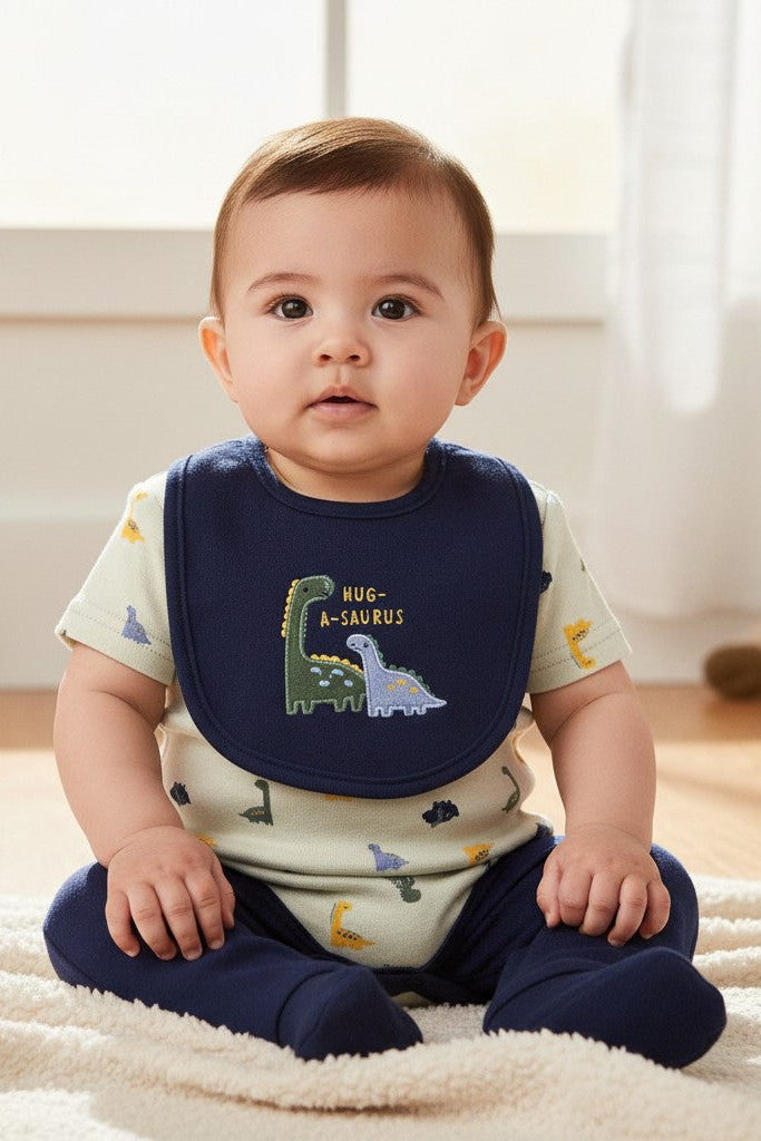 Calla Lily Cosmetics + CL kids 3-piece baby set with dinosaur print bodysuit, navy pants, and bib. 60% Cotton, 40% Polyester.