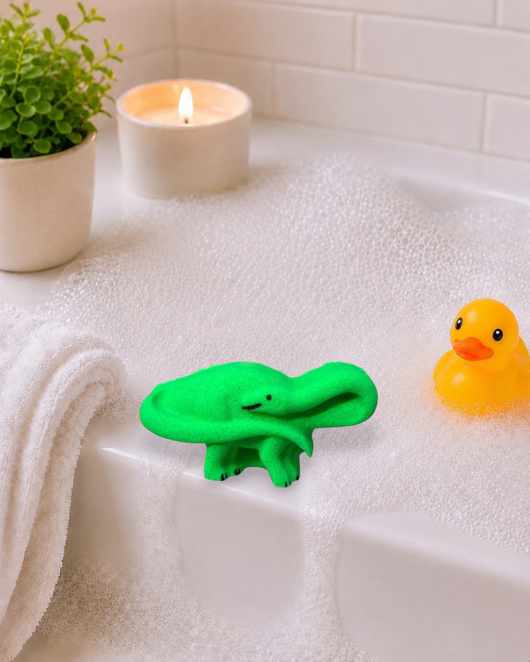 Calla Lily Cosmetics + CL kids green brontosaurus dinosaur bath bomb with citrus scent on a neutral tray.