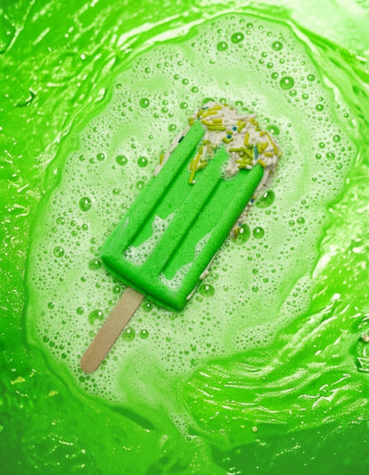 Calla Lily Cosmetics + CL kids green popsicle bath bomb fizzing in water with white sprinkles and wooden stick