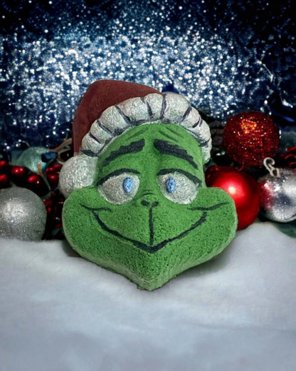 Calla Lily Cosmetics + CL kids hand painted green Grinch bath bomb with a Santa hat, set against festive ornaments.