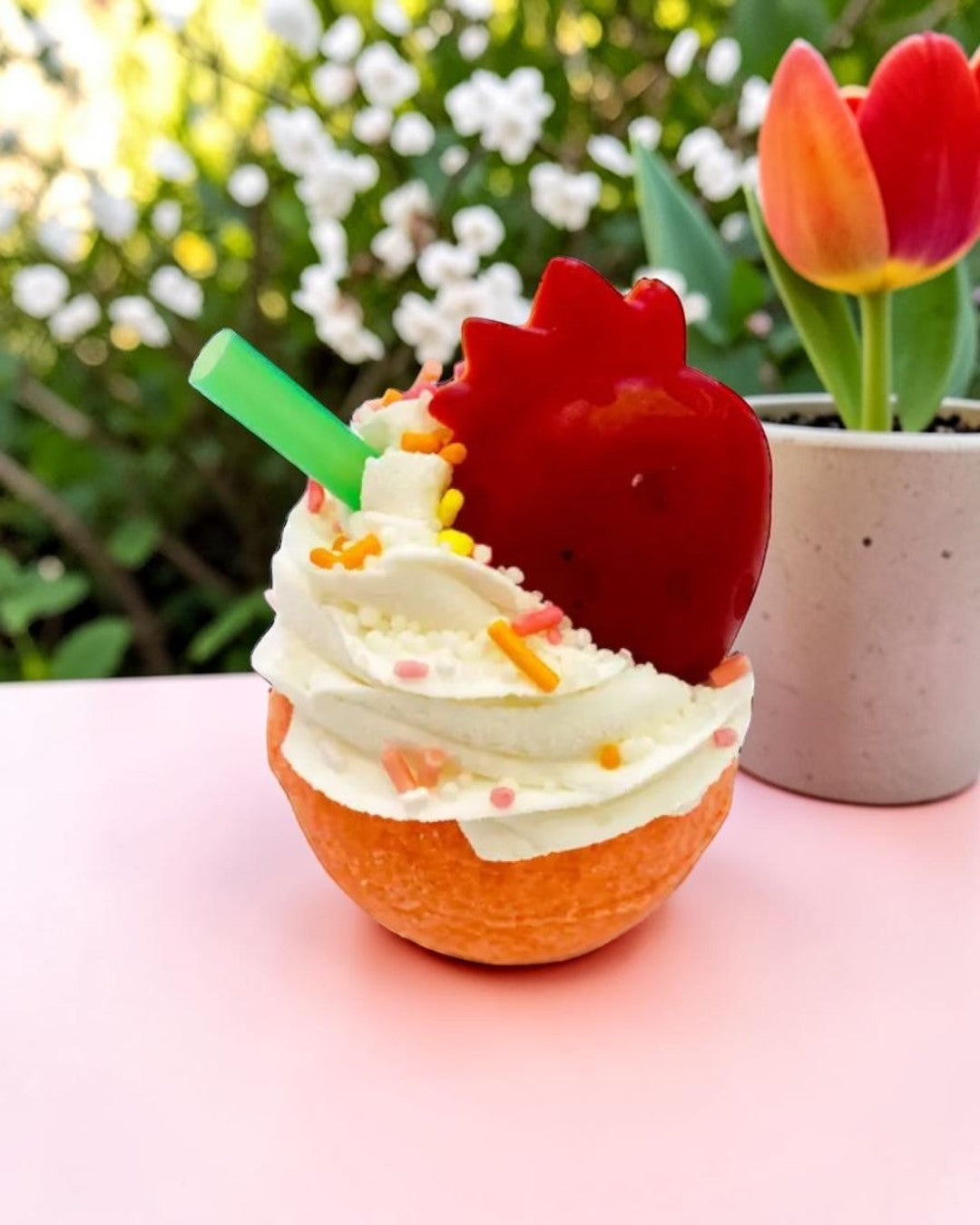 Calla Lily Cosmetics + CL kids orange cupcake bath bomb with white frosting, strawberry topper, and green straw.