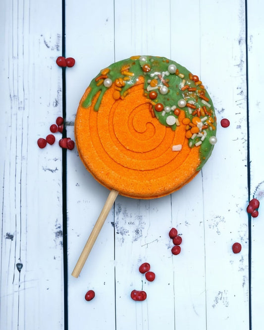 Calla Lily Cosmetics + CL kids orange lollipop bath bomb with green icing, sprinkles, and a wooden stick