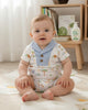 Calla Lily Cosmetics + CL kids white organic cotton baby romper with blue collar and safari print of lions, elephants, giraffes, zebras, and trees.