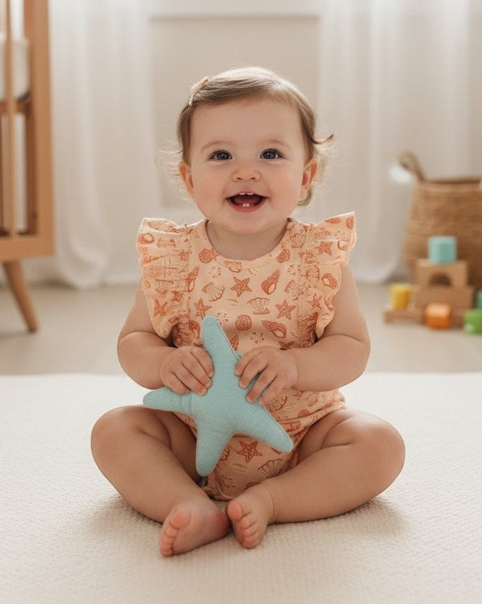 Calla Lily Cosmetics + CL kids peach cotton romper with seashell and starfish print and ruffled sleeves.