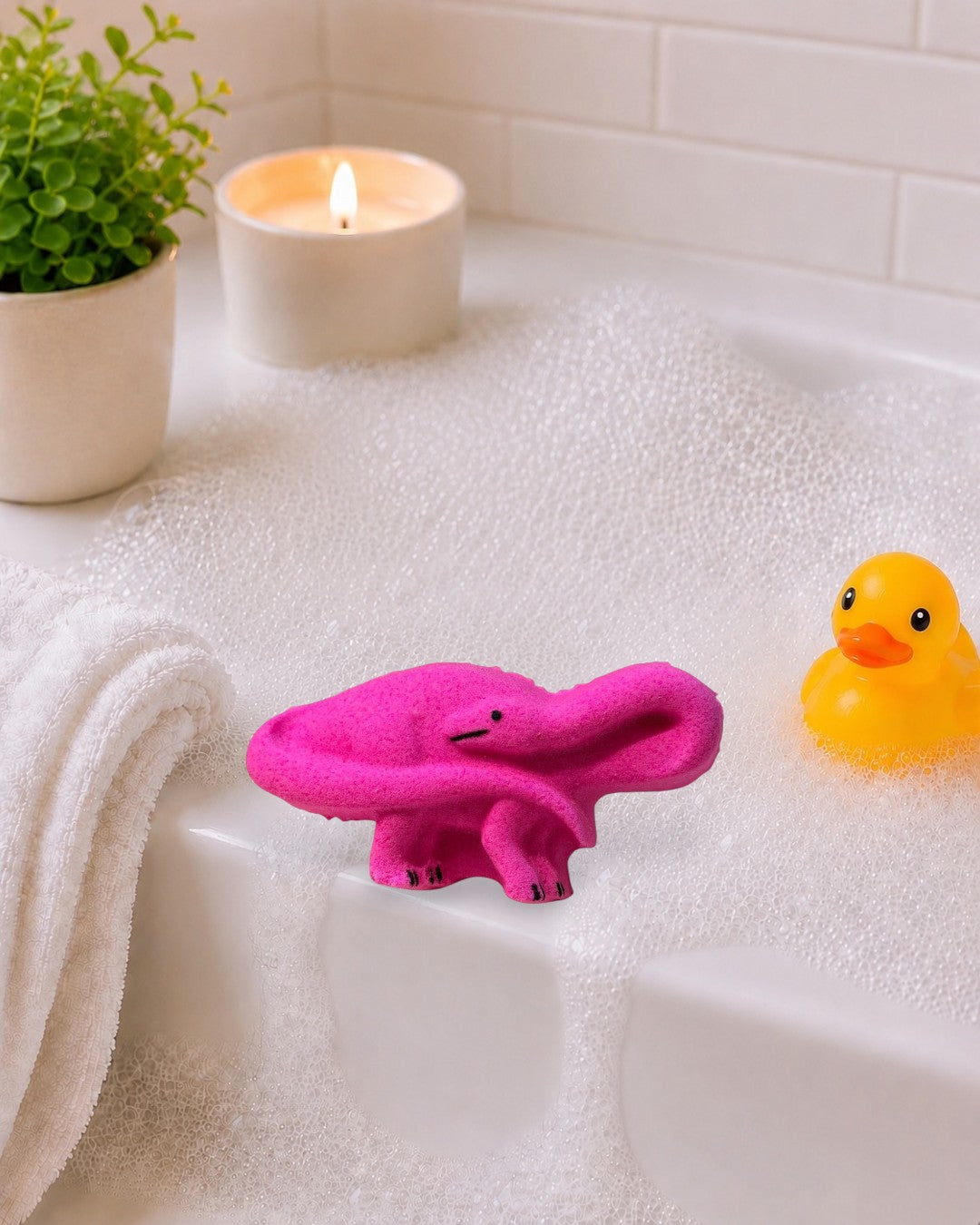 Calla Lily Cosmetics + CL kids pink strawberry-scented brontosaurus dinosaur bath bomb on a white wood background