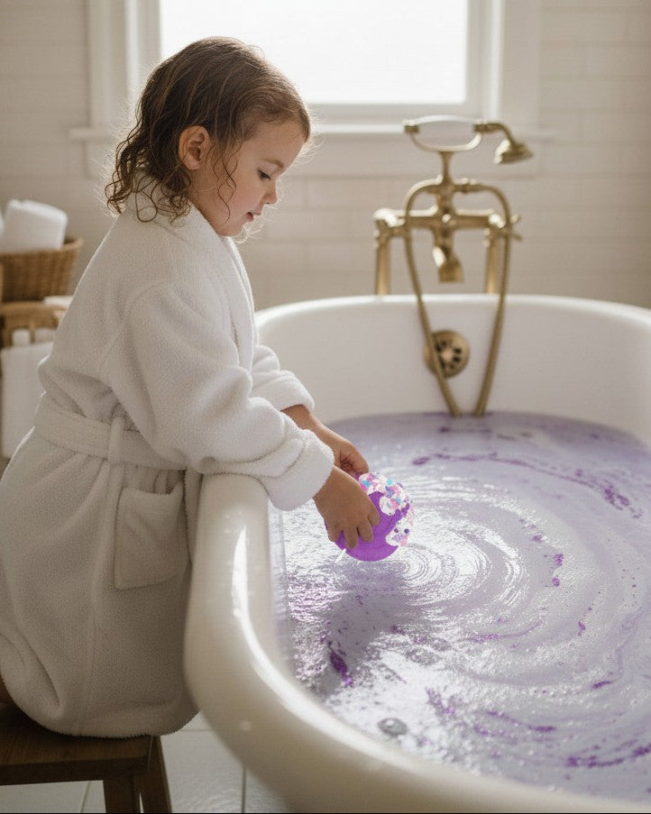 Calla Lily Cosmetics + CL kids purple lollipop bath bomb fizzing in a bathtub with a child in a white robe