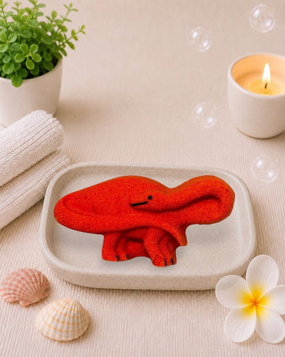 Calla Lily Cosmetics + CL kids red brontosaurus shaped bath bomb with blood orange scent on a small tray