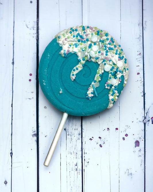 Calla Lily Cosmetics + CL kids teal lollipop bath bomb with white icing and colorful sprinkles on a wooden surface