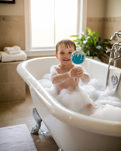 Calla Lily Cosmetics + CL kids teal lollipop bath bomb held by a smiling child in a bubble-filled bathtub