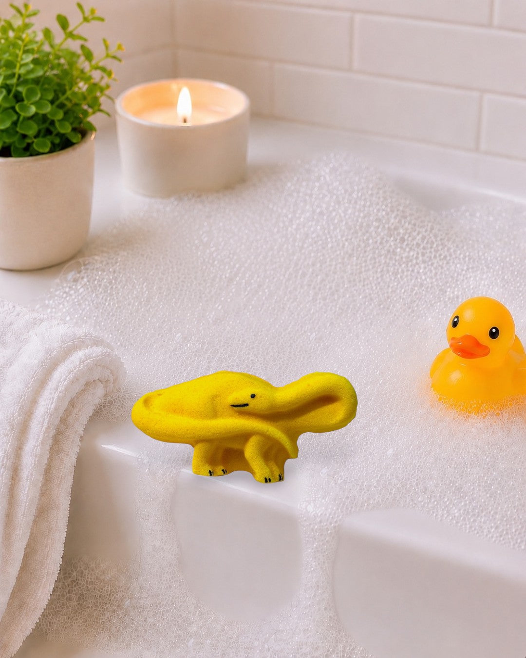 Calla Lily Cosmetics + CL kids yellow brontosaurus shaped pineapple scented bath bomb on a white wood background