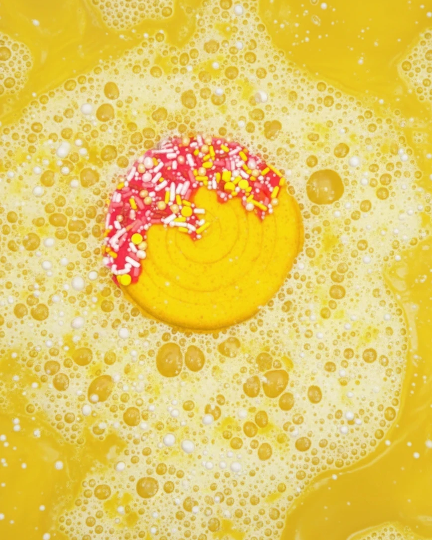 Calla Lily Cosmetics + CL kids yellow pineapple-scented lollipop bath bomb fizzing in a bubbly bath with sprinkles