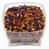 A clear square plastic container filled with loose-leaf herbal tea blend, featuring dried flowers and botanical pieces in orange, brown, purple, and red tones, shown against a plain white background.