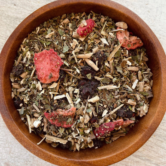 Herbal tea mix with dried strawberries and other ingredients in a wooden bowl.