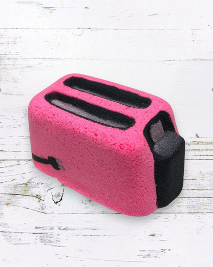 Calla Lily Cosmetics + CL kids pink toaster-shaped bath bomb with strawberry scent on a white wooden surface