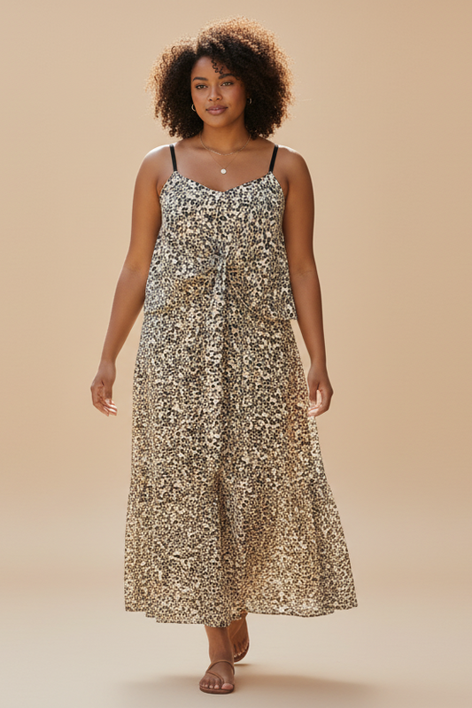 Woman in a floral dress standing on a sunlit street with plants and buildings in the background