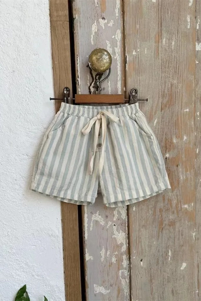 Striped shorts with a tie waist hanging on a wooden door.