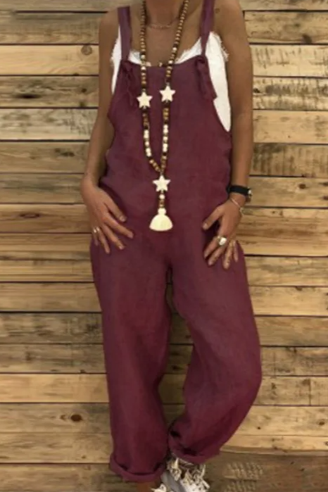 Person wearing a burgundy jumpsuit with a wooden wall background