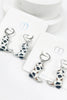 Silver cowboy boot earrings on a white card with 'm' branding.