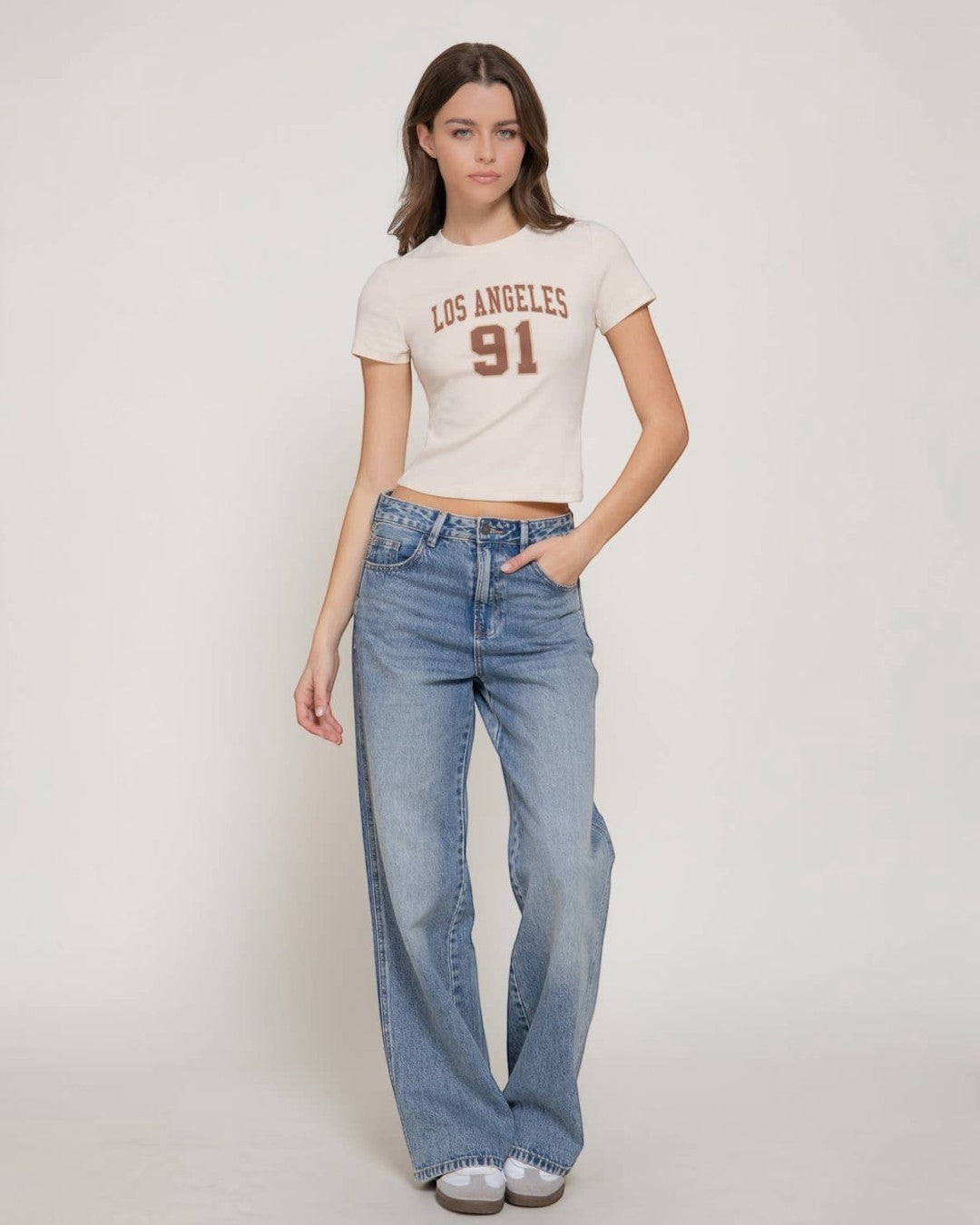 Woman wearing a 'Los Angeles 91' t-shirt and blue jeans on a white background