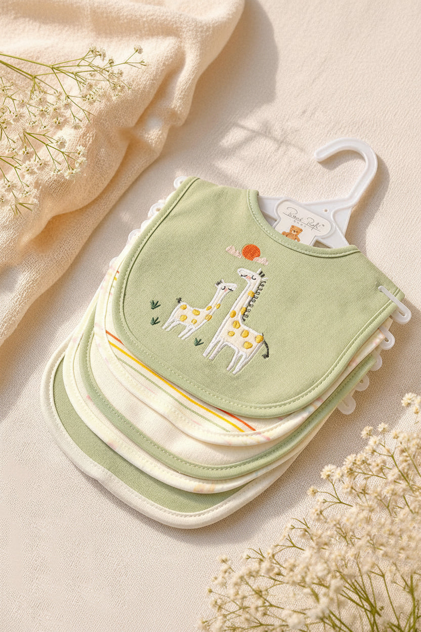 Stack of green baby bibs with giraffe design on a beige background