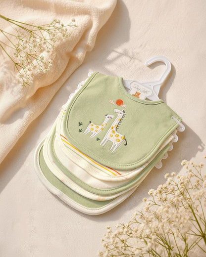 Stack of green baby bibs with giraffe design on a beige background