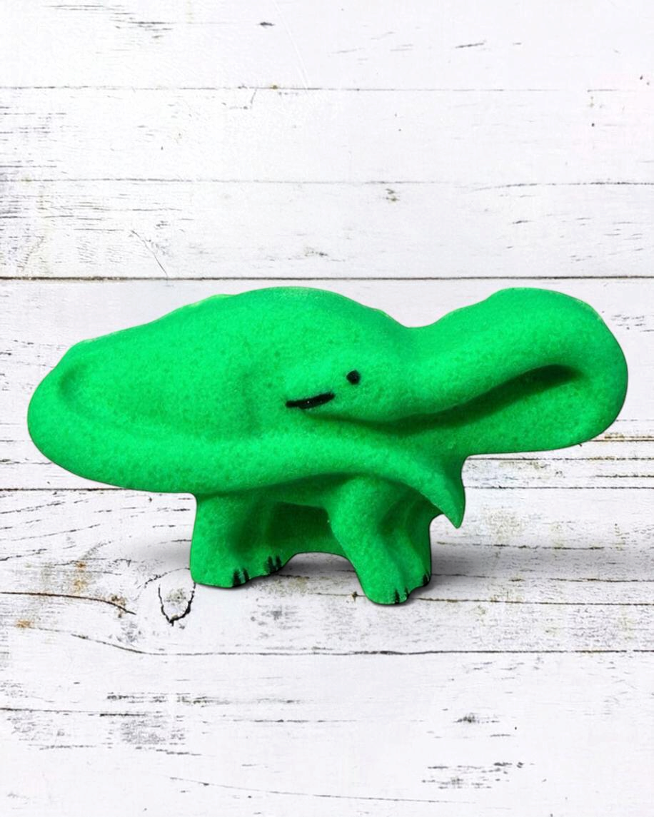 Calla Lily Cosmetics + CL kids green brontosaurus dinosaur bath bomb with citrus scent on a white wood background
